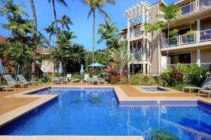 维雷亚Wailea Grand Champions Villas - CoralTree Residence Collection的棕榈树建筑前的游泳池