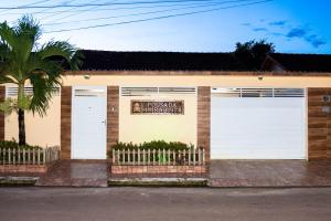 帕林廷斯Pousada Muiraquitã Parintins的一座建筑,设有两扇白色的车库门和棕榈树