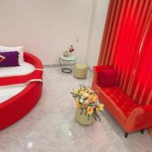Bến CátHappy 2 Hotel Bình Dương的一间卧室配有红色的床、椅子和鲜花