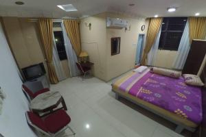 北干巴鲁Utama Syariah的一间卧室配有一张紫色的床和椅子