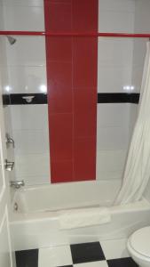 洛杉矶好莱坞传奇酒店的浴室设有白色浴缸和红色瓷砖墙。