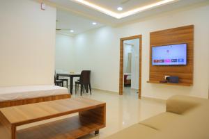 蒂鲁帕蒂Padma Homes Stay- Luxury Service Apartment 1BHK & 2BHK & 3BHK的客房设有1张床、1张桌子和1台电视。
