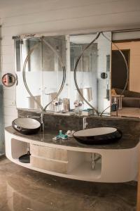 瓦加托W果阿度假村的一间带两个盥洗盆和大镜子的浴室