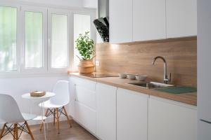 塞维利亚Magno Apartments Miño的厨房配有白色橱柜、水槽和桌子