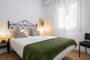 塞维利亚Magno Apartments Miño的卧室配有一张带绿毯的大型白色床