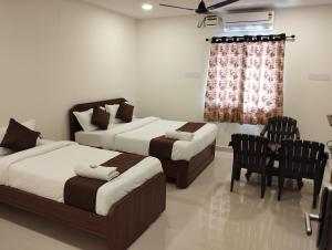 海得拉巴HOTEL VIRAT GRAND的一间卧室配有两张床和一张桌子及椅子