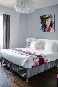 拉罗谢尔Le Manoir Hôtel的卧室配有一张大床,墙上挂有绘画作品
