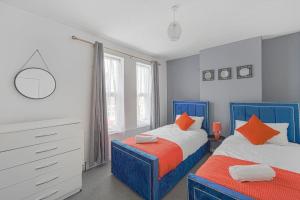 埃德蒙顿The Marsden - Modern 3 bed, Virgin TV, WIFI的卧室内的两张床,配有蓝色和橙色枕头