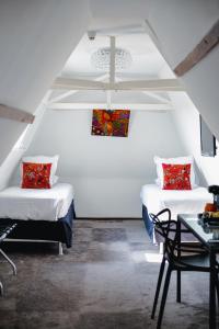 拉罗谢尔Le Manoir Hôtel的白色客房内的两张床,配有桌子和椅子