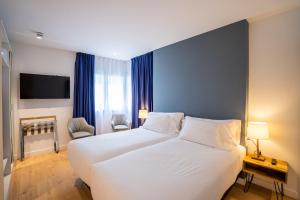 圣塞瓦斯蒂安abba Apartments Playa de Gros San Sebastián的卧室配有白色大床和蓝色的墙壁