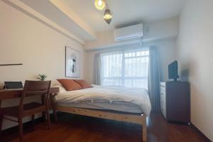 东京Saison Daikanyama - Ebisu Nishi的一间卧室配有一张床、一张书桌和一个窗户。