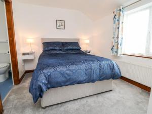 弗罗德舍姆91 Main Street的一间卧室配有一张带蓝色棉被的床和窗户。