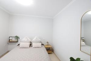里瓦德奥Casa Flor Delfin Ribadeo的白色卧室配有床和镜子