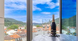海德堡PLAZA Premium Heidelberg的窗户前的桌子上放着一瓶葡萄酒和两杯酒