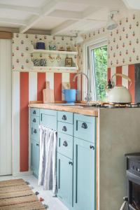 博德明Fleur de Grog - Shepherds Hut的厨房配有蓝色橱柜和窗户。