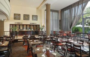 勒斯滕堡StayEasy Rustenburg的餐厅设有木桌、椅子和窗户。