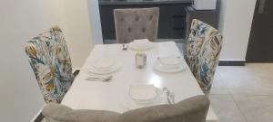 内罗毕City Haven Accommodation-Two bedroom Apartment的一张桌子、两把椅子和一张带板子的白色桌子