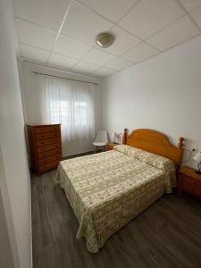 穆拉Apartamento Gabarron的一间卧室配有一张床、一个梳妆台和一扇窗户。