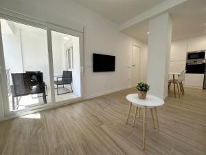 帕尔斯Apartamento Galiria, Pals的白色的客厅配有桌子和电视。