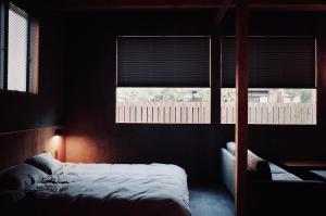 洲本市MAGATAMA.INN的一间卧室设有一张床和两个窗户。
