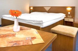 塔查斯卡-鲁穆尼卡Hotel SOREA TITRIS的一间酒店客房,配有一张床铺和一张桌子,上面有花