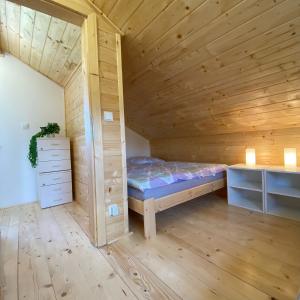 SloupChata Pod kaplí的一间小卧室,配有一张位于木制房间内的床