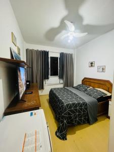里约热内卢MARAVILHOSO QUARTO E SALA até 4 PESSOAS NO LEBLON na Av ATAULFO DE PAIVA的一间卧室配有一张床、一张书桌和一台电视