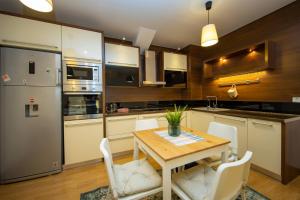 普里什蒂纳Apartments PRN的厨房配有木桌和白色椅子
