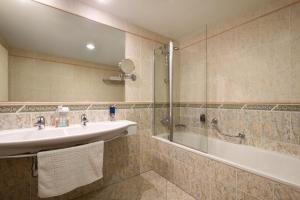 布拉格华美达布拉格市中心酒店的浴室配有水槽、淋浴和浴缸。