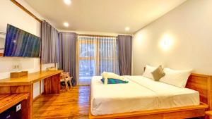 吉利特拉旺安宁静海滩别墅的一间卧室配有一张床、一张书桌和一个窗户。