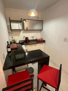 福塔莱萨952A golden fortaleza的一间小厨房,配有黑色柜台和红色椅子
