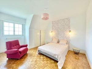 坡隆维茨普尔扎伊LA VILLA STE ANNE - Wifi - Plages et bourg de Plonevez à 2 min的一间卧室配有一张床和一张粉红色的椅子