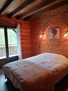 马尼戈Chalet de Manigod的卧室配有一张床铺,位于带木墙的房间内