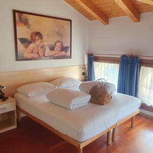 加尔达湖滨GARDAINN La CASCINA的卧室配有一张白色床,墙上挂有绘画作品