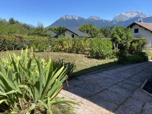 圣若里奥Saint-Jorioz Maison , vue montagnes, jardin clos , 8pers的一座花园,其背景是一座房子和山脉