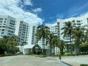 阿卡普尔科Departamento Playa Punta Diamante的一座白色的大建筑,前面有棕榈树