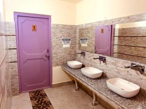 列城Milam Hostel的一间带两个水槽和紫色门的浴室