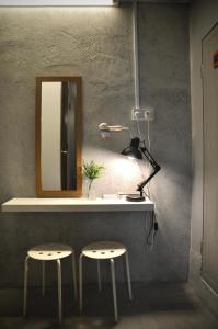 怡保GRAYHAUS INN Ipoh的梳妆台,配有2把凳子、镜子和灯