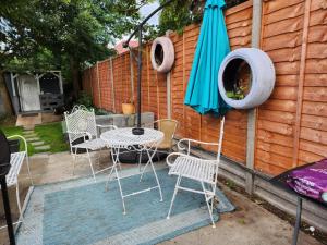 South NorwoodSpacious Room with Garden in Croydon London的庭院配有桌椅和遮阳伞。