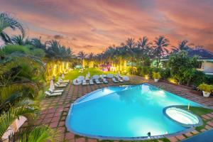 坎多林O Hotel Goa, Candolim Beach的享有带椅子和棕榈树的游泳池的顶部景致