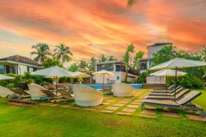 坎多林O Hotel Goa, Candolim Beach的院子里的一组躺椅和遮阳伞