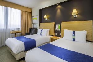 佩斯利假日格拉斯哥机场酒店的酒店客房,配有两张床和椅子