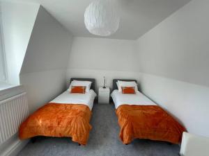 波尔蒙特Fantastic home in Brightons, Falkirk.的配有白色墙壁和橙色枕头的客房内的两张床