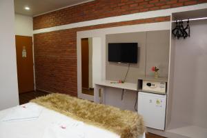 皮拉尼亚斯Pedra do Sino Hotel的一间卧室设有床铺、电视和砖墙