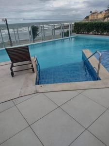 伊塔尼亚恩Lindo Apartamento na Praia do Sonho的毗邻大海的带长凳的游泳池