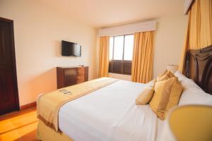奇南德加罗斯波塔利斯酒店的卧室设有一张白色大床和一扇窗户。