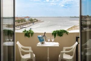 格拉多Hotel Eden的阳台配有桌椅,享有海景。