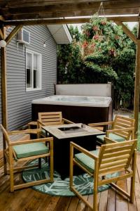基洛纳Charming Kelowna Haven with Hot Tub, Parking, Pet-Friendly Bliss的庭院设有三把椅子、一张桌子和一个浴缸。
