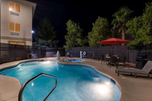 拉斯维加斯Comfort Inn & Suites Las Vegas - Nellis的夜间游泳池,配有桌子和遮阳伞
