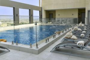 吉达Clarion Hotel Jeddah Airport的大楼内带躺椅的大型游泳池